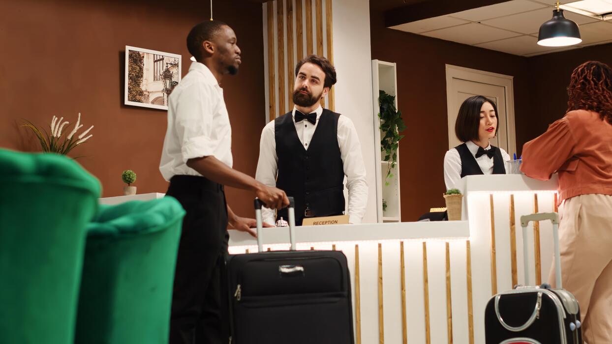 Recepción de hotel atendiendo a huéspedes con equipaje